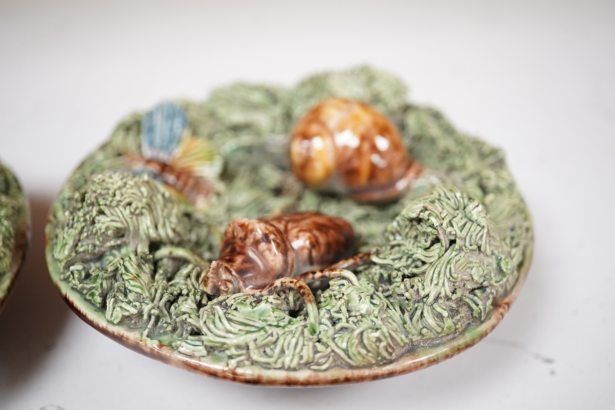 A pair of late 19th century Portuguese small circular Palissy style majolica plaques incorporating lizard and snail and with a mossy ground, impressed marks to reverse, 12cm diameter. Condition - fair